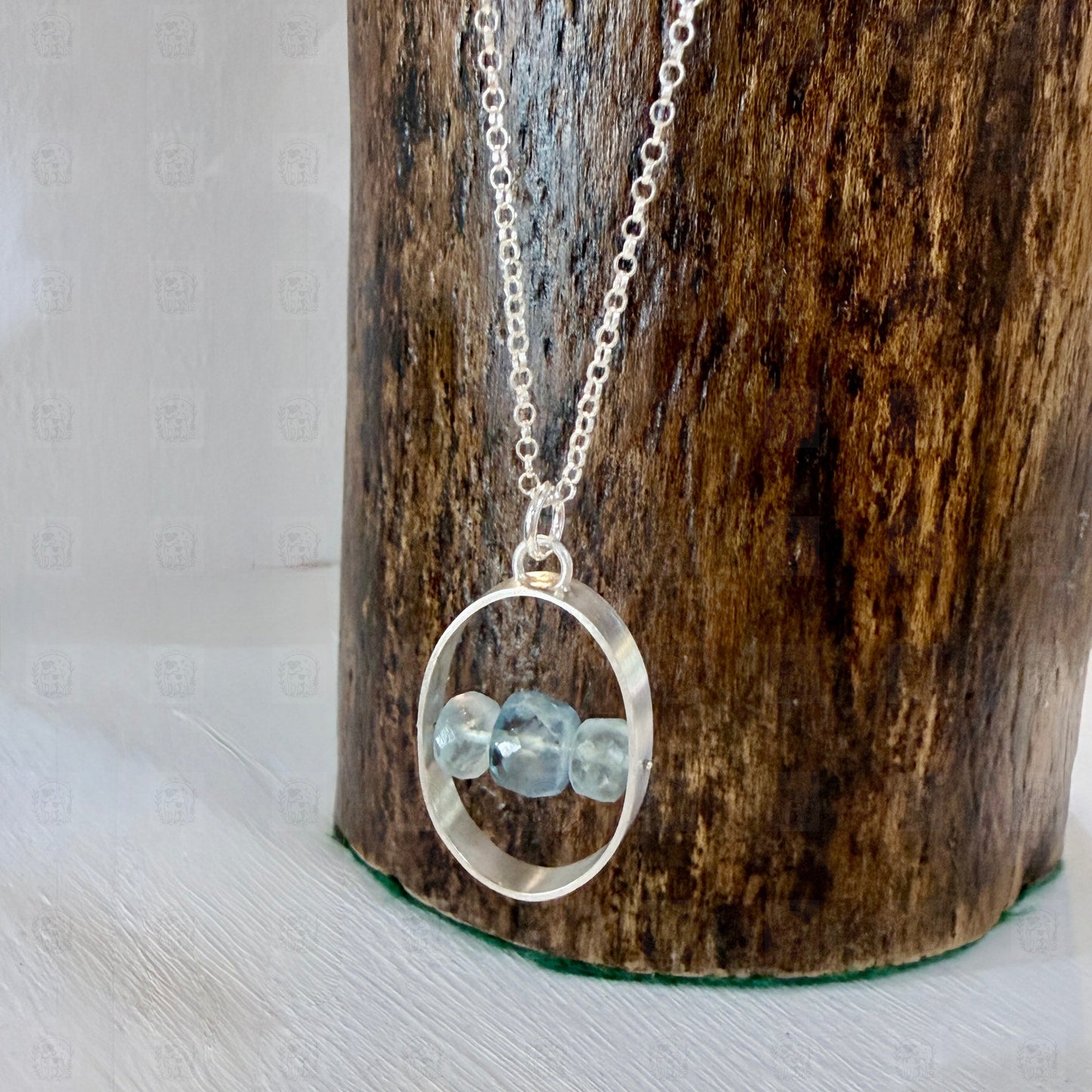 A sterling silver and aquamarine pendant on a wooden background