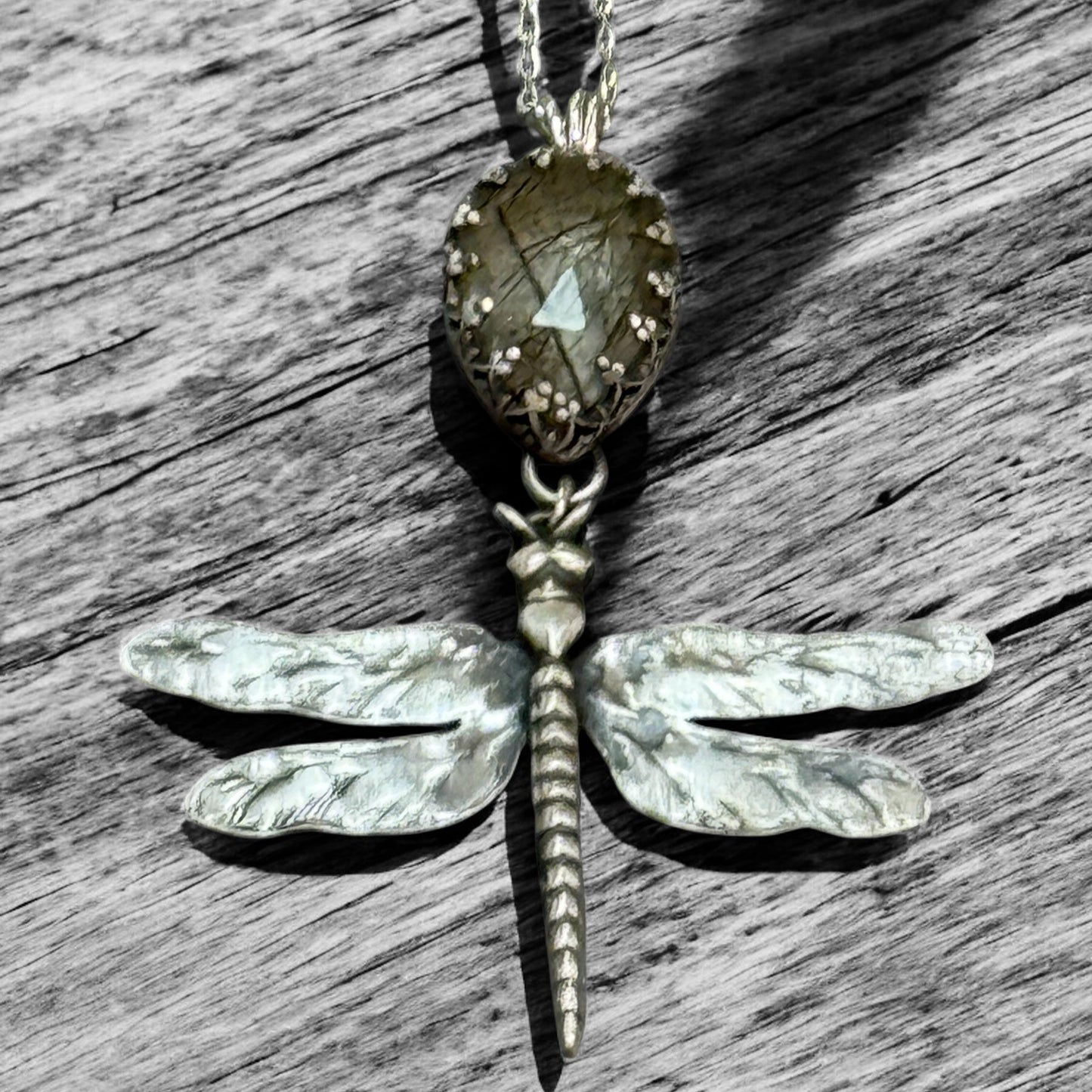 Dragonfly-shaped pendant necklace on a wooden surface