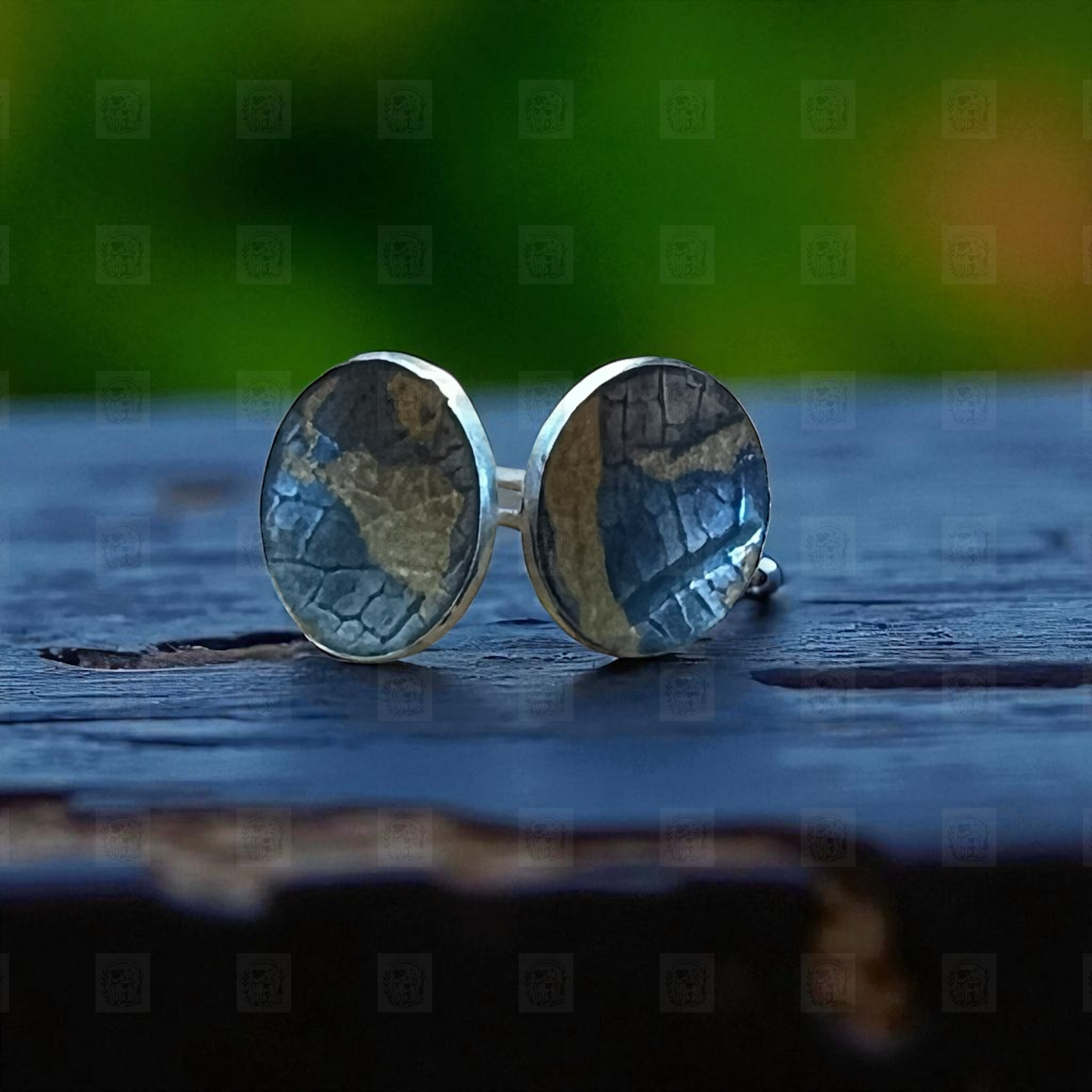 Round silver earrings with a textured design on a wooden surface.