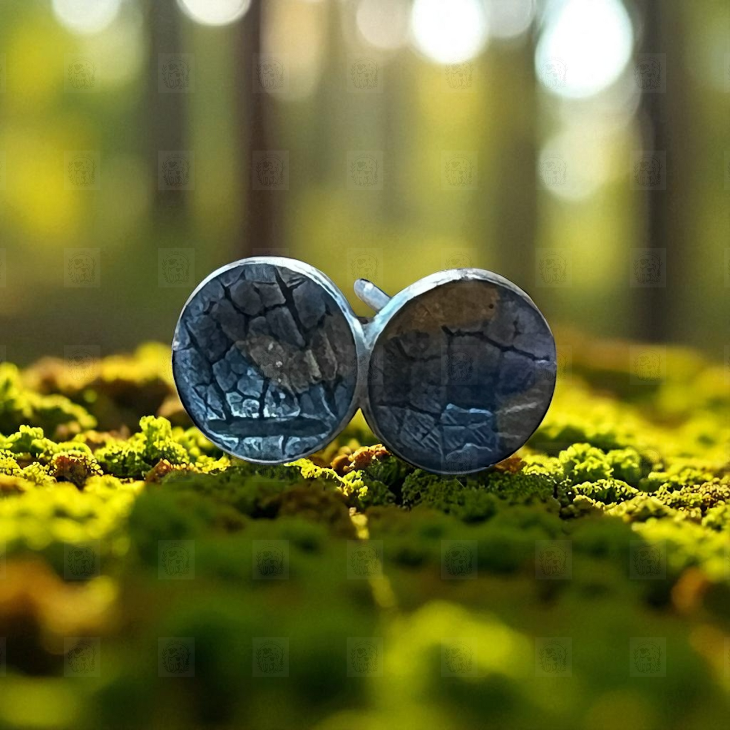 Pair of round earrings with a textured surface on a green moss background