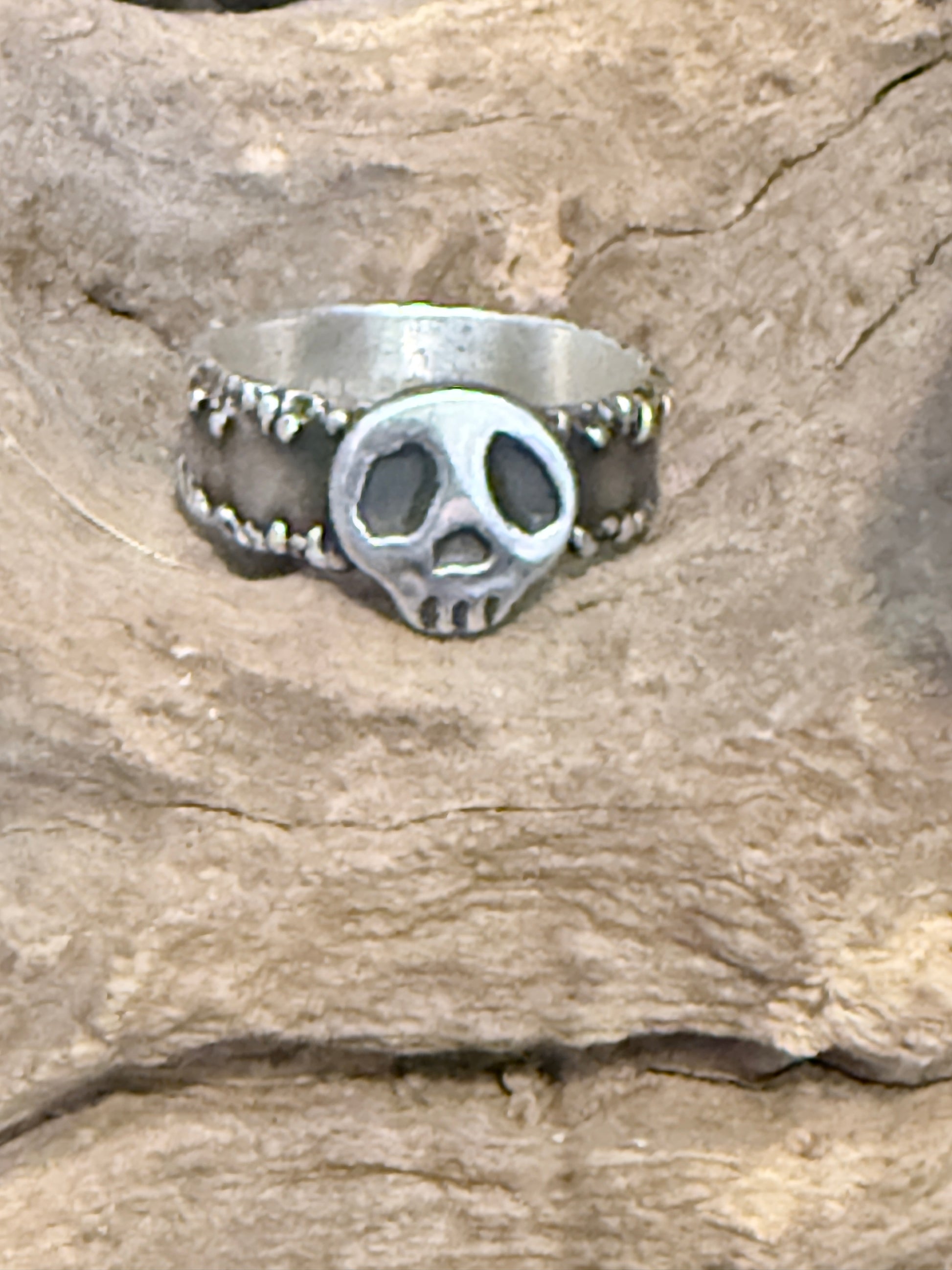 Silver ring with a friendly skull on a stone background