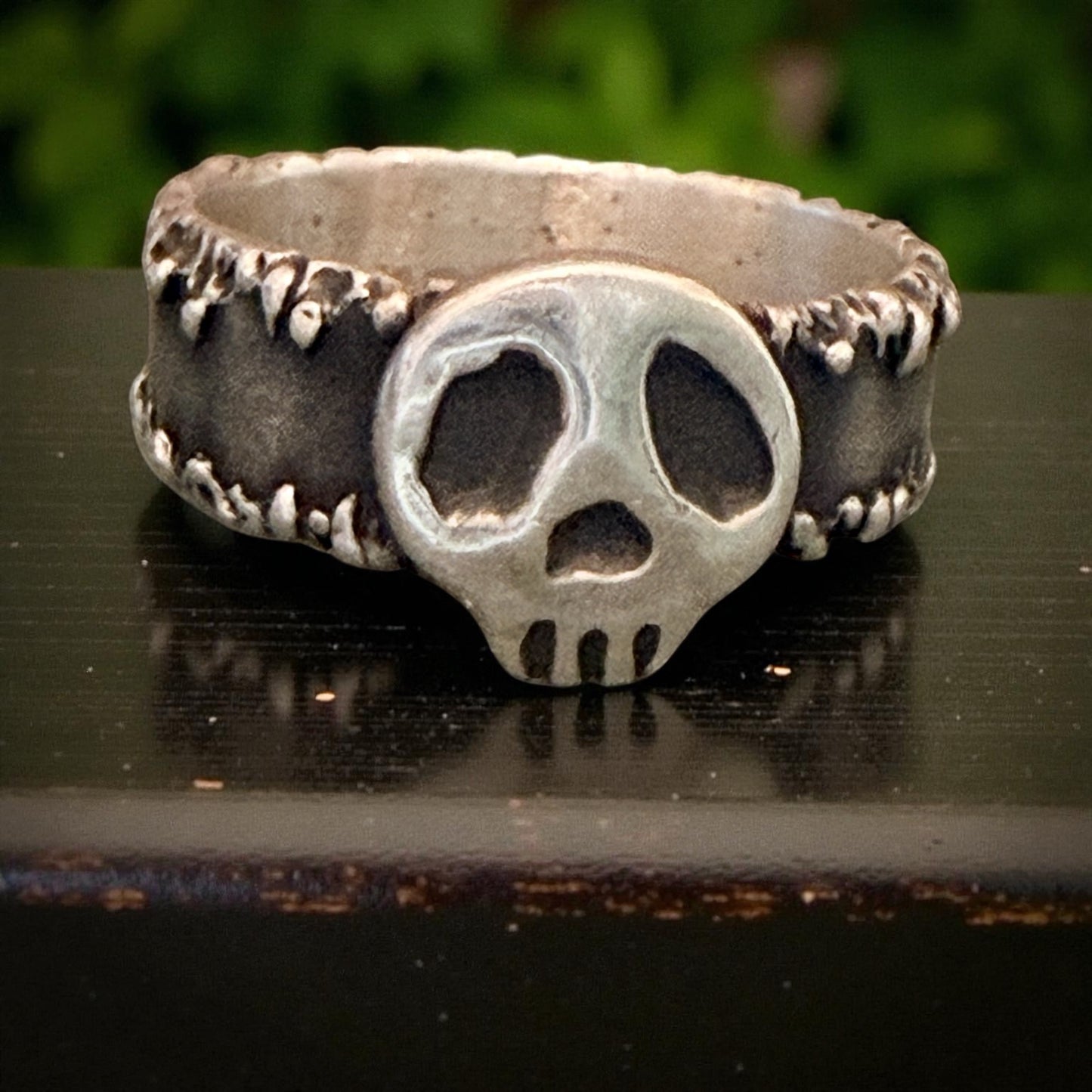 Skull-shaped ring with detailed design on a dark surface