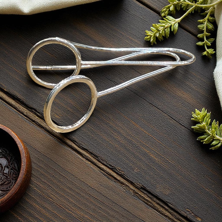 Silver earrings on a wooden surface with greenery