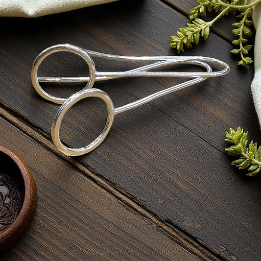 Silver earrings on a wooden surface with greenery