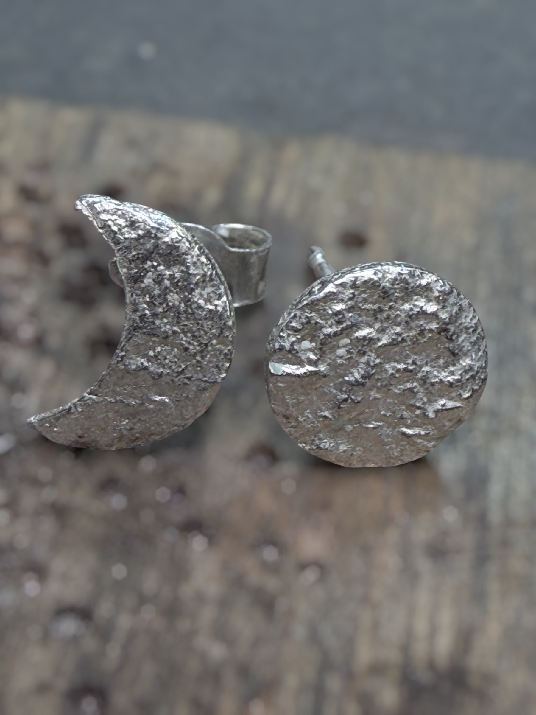 Silver textured moon and circle earrings on a wooden surface