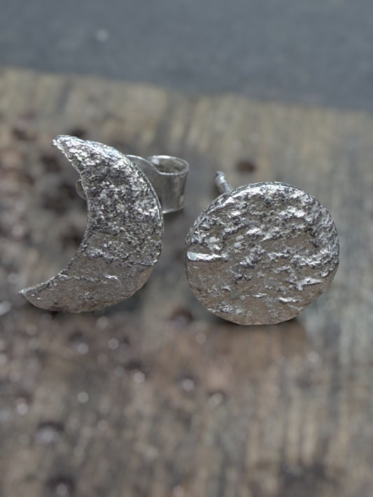 Silver textured moon and circle earrings on a wooden surface