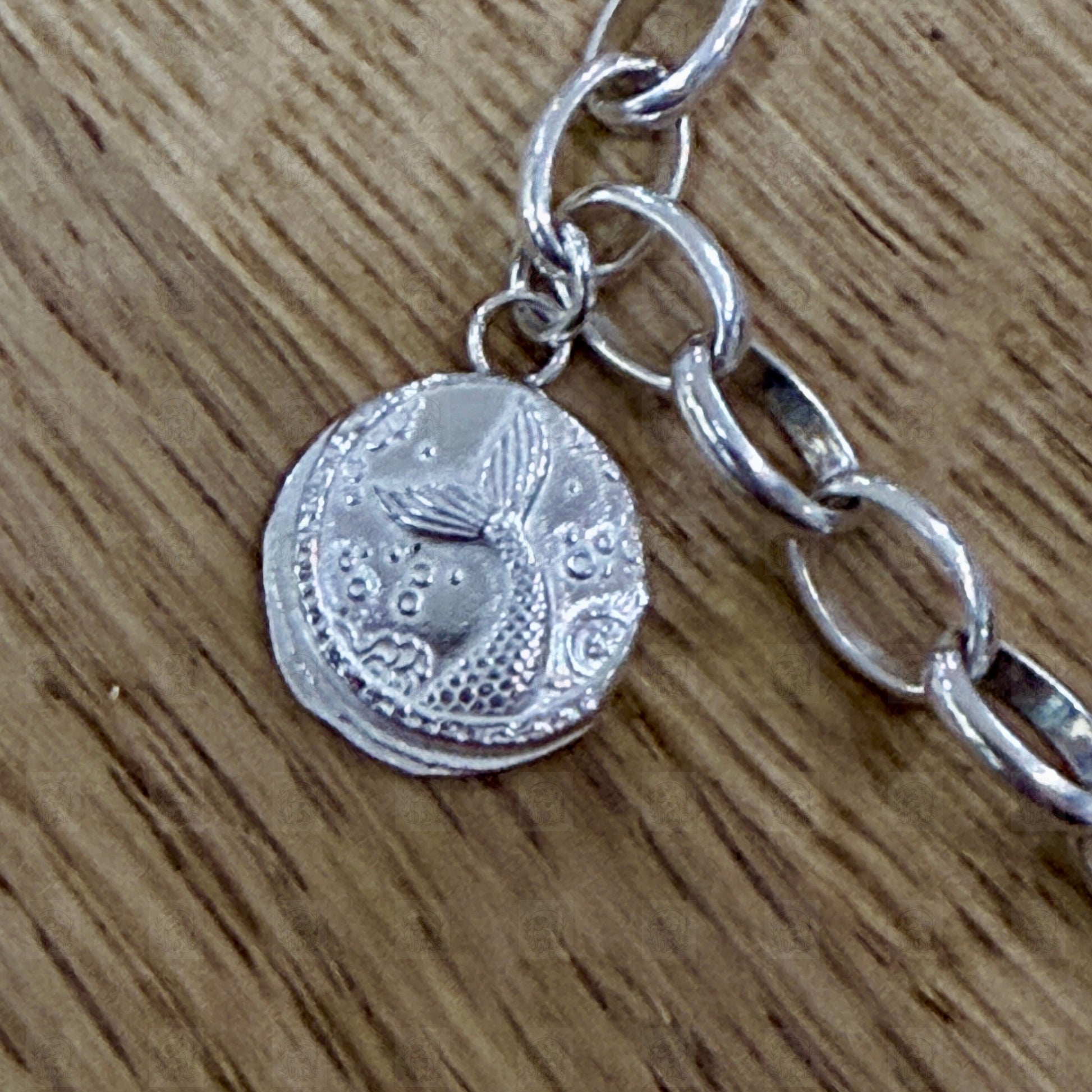 A close up of a mermaid tail charm on a wooden background