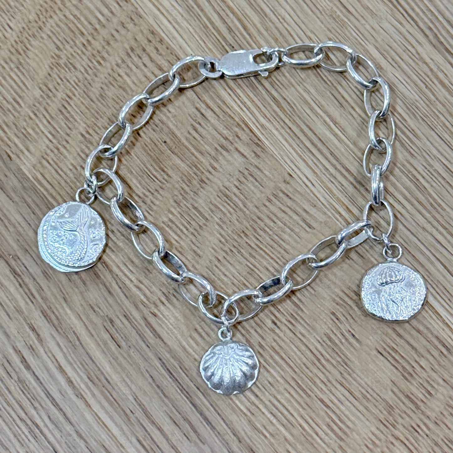 A sea themed charm bracelet on a wooden background