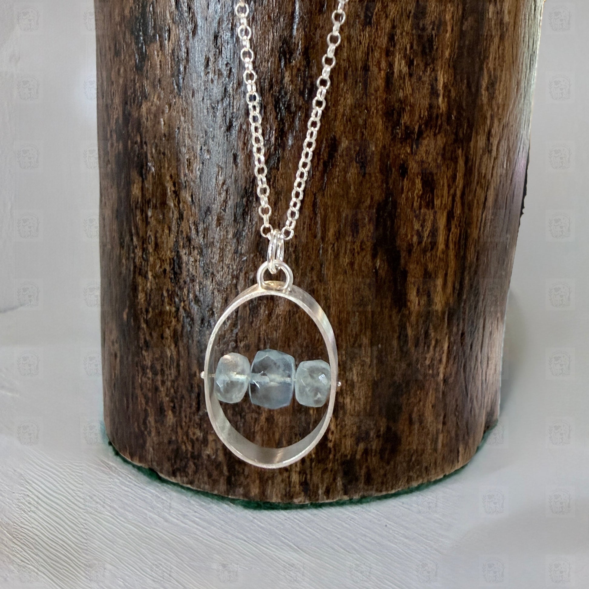 A sterling silver and aquamarine pendant on a wooden background