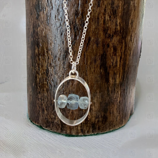 A sterling silver and aquamarine pendant on a wooden background