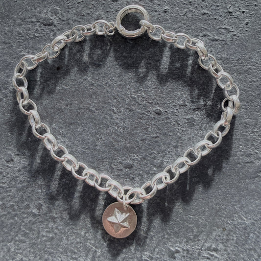 Silver chain bracelet with a star charm on a dark stone surface