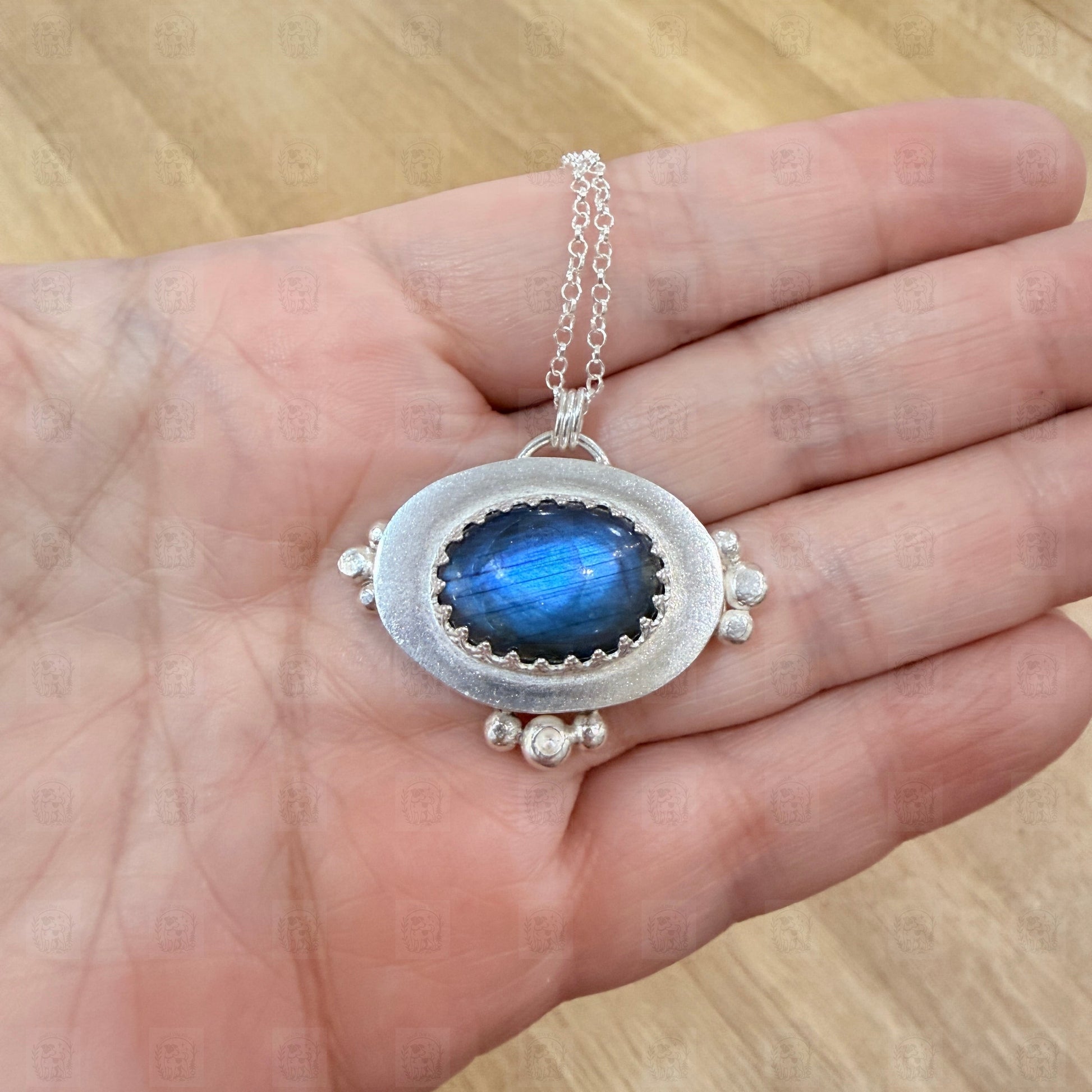 A sterling silver and labradorite pendant held in a hand.