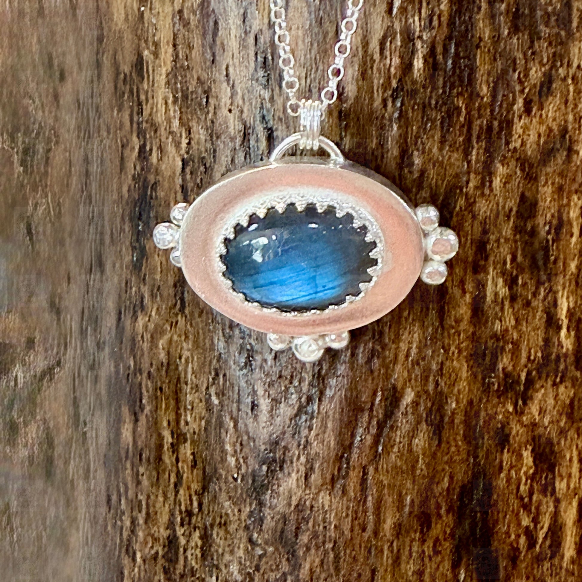 A sterling silver and labradorite pendant on a wooden background