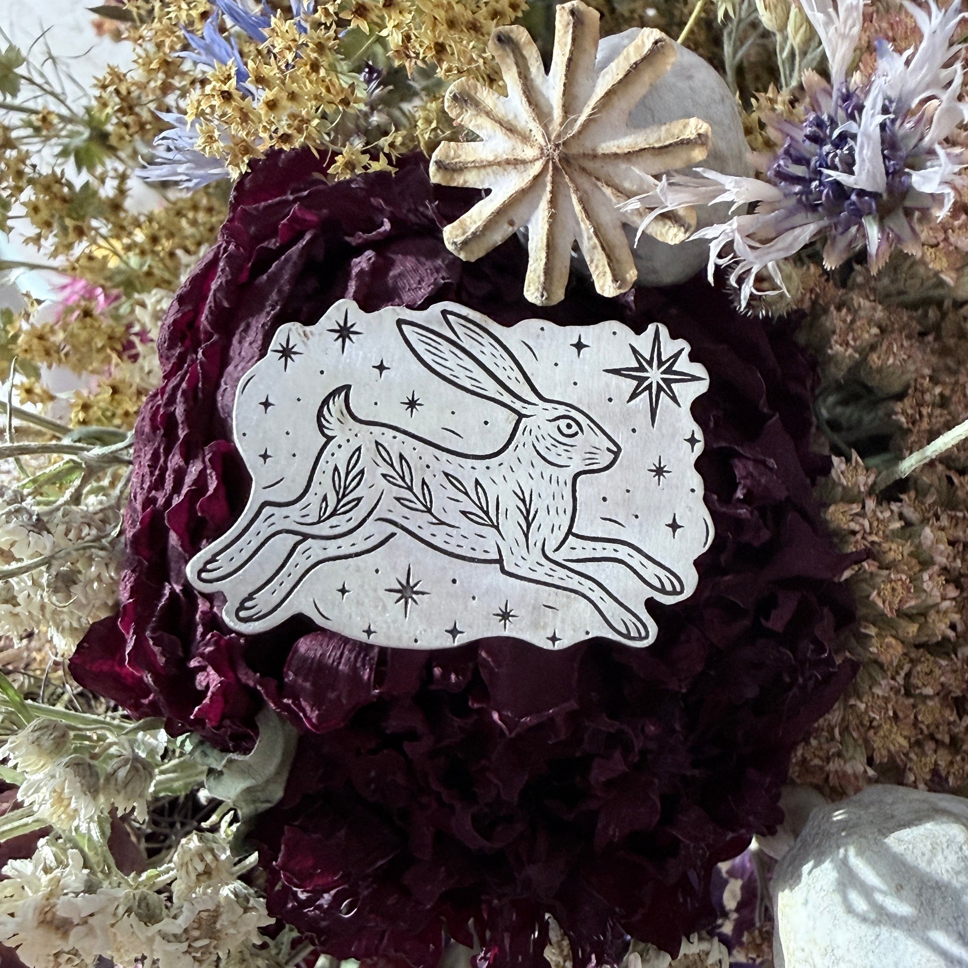 Silver brooch with etched hare on a dried flower background